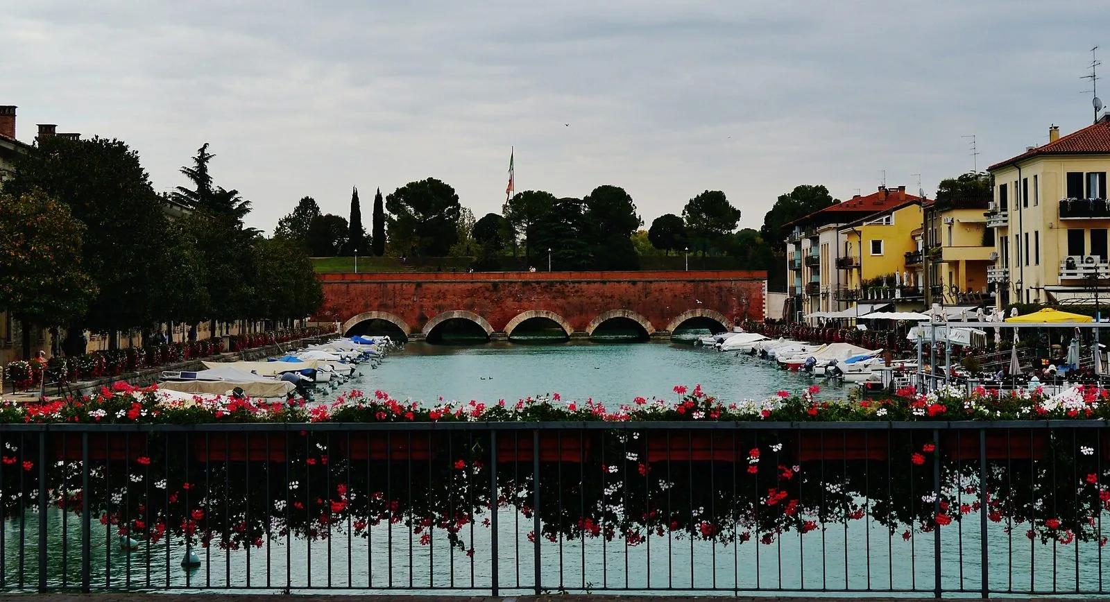 Il Canale di Mezzo a Peschiera del Garda con barche ormeggiate, case colorate e il ponte in pietra
