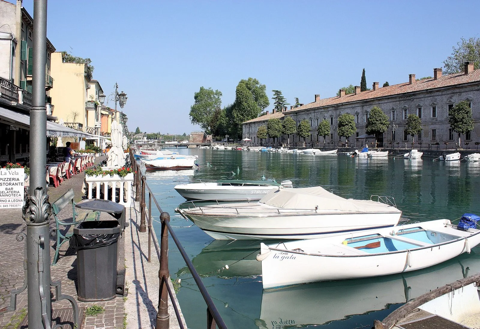 Il porto e il lungolago di Peschiera del Garda in una giornata estiva affollata, con barche ormeggiate