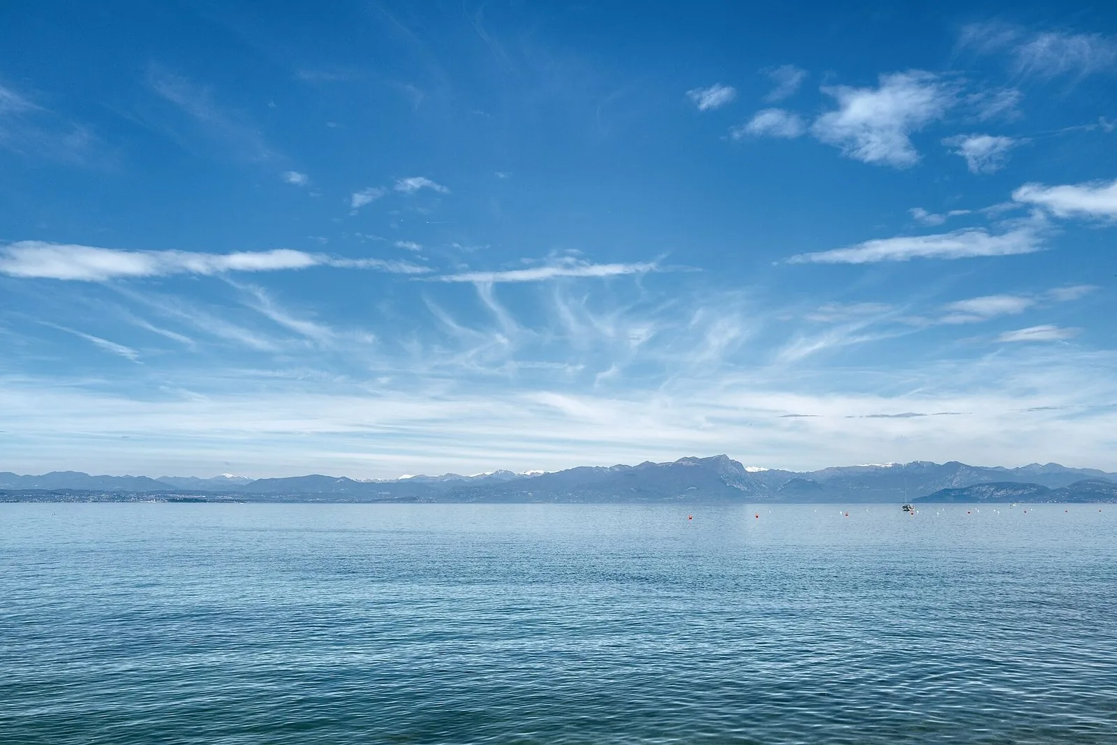 Il Lago di Garda in primavera a Peschiera, con alberi in fiore e acqua calma